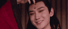 a man with long hair and a tattoo on his forehead is smiling