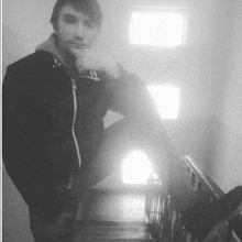 a young man is sitting on a set of stairs with his hand on his chin
