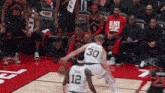 a basketball player with the number 30 on his jersey tries to get past another player