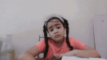 a little girl with braids sits at a table with an open book