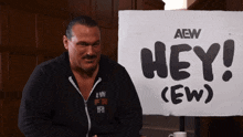a man is sitting in front of a sign that says hey