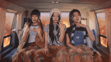 three girls are sitting in the back of a van