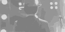 a man in a suit and hat is singing into a microphone .
