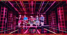 a group of girls are dancing on a stage in a room with neon lights .