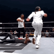 a man is laying on the ground in a wrestling ring while a woman in a white suit runs towards him