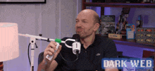 a man is holding a remote control in front of a microphone and the words dark web are on the bottom