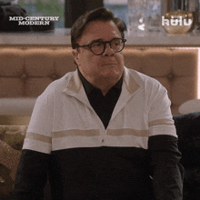 a man is sitting on a couch in front of a hulu ad