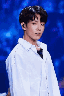 a young man wearing earphones and a white shirt is standing on a stage .