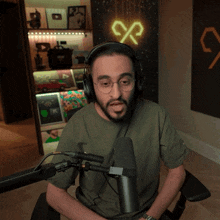 a man wearing headphones sits in front of a microphone in front of a neon sign that says cp
