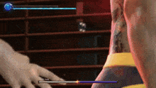 a person with a tattoo on their back is playing a video game and pointing at the screen .