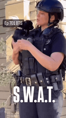 a woman in a swat uniform holds a small dog