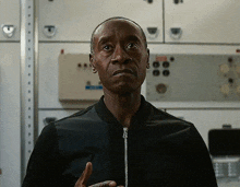 a man in a black jacket is standing in front of a white wall