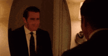 a man in a suit is looking at himself in a mirror .