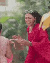 a woman in a red dress is laughing and hugging another woman in a pink dress .