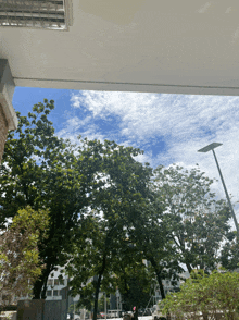 a view of a street with trees and a blue sky with white clouds