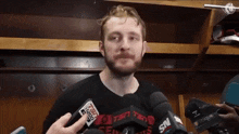 a man with a beard is talking into a microphone while wearing a shirt that says espn