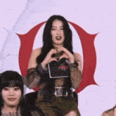 a woman is making a heart shape with her hands in front of a red o .