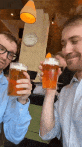 two men toasting with glasses of beer in front of a clock that says 12:37