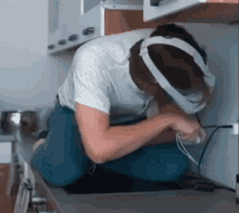 a man wearing headphones and a headband is kneeling on a kitchen counter .