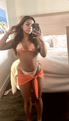 a woman in a bikini takes a selfie with her phone
