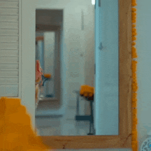 a woman in a yellow dress is looking at herself in a mirror .
