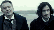 two men are standing next to each other and one of them has a pin on his jacket