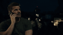 a man in a green shirt is talking on a cell phone .