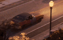 a car is driving down a street with a street light in the foreground