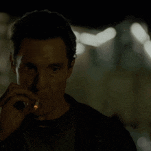 a man smoking a cigarette in the dark