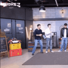 three men are dancing in a room with a sign that says ' x2o ' on it