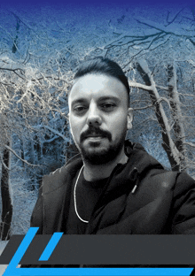 a man with a beard is standing in front of snowy trees