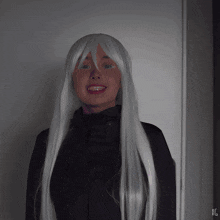 a woman wearing a white wig and a black jacket stands in front of a white wall with the letters xg on it