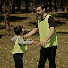 a man in a yellow vest is talking to a young boy