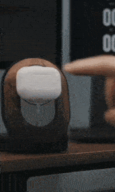 a person 's finger is pressing a button on a wooden charger