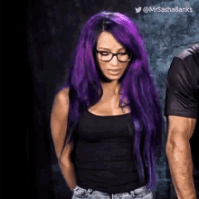 a woman with purple hair and glasses is standing next to a man in a black shirt .