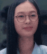 a woman wearing glasses and a blue shirt smiles