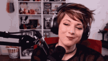 a woman wearing headphones is smiling in front of a microphone