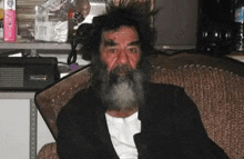 a man with a beard and mustache is sitting in a chair .