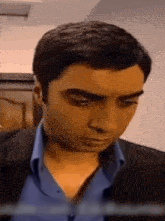 a close up of a man in a suit and blue shirt looking down .