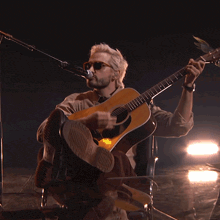 a man playing a guitar and singing into a microphone