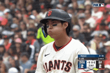 a baseball player wearing a giants jersey looks at the scoreboard