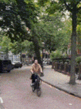 a man is riding a bike down a street with the letter x on the bottom right