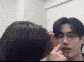 a man wearing glasses is being touched by a woman 's hand