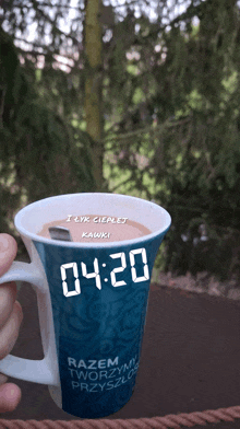 a person is holding a blue mug that says 4:20 on it