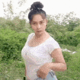 a woman in a white t-shirt and blue jeans is standing in a field .