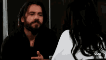 a man and a woman are sitting at a table with their eyes closed and talking to each other .