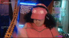 a woman wearing a pink hat and headphones is standing in front of a halloween decoration