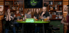 a group of people sitting at a table in front of a tv that says x-time