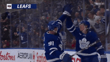 two leafs players high five each other in front of the crowd