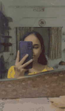 a girl with purple hair is taking a selfie with her cell phone in front of a mirror .